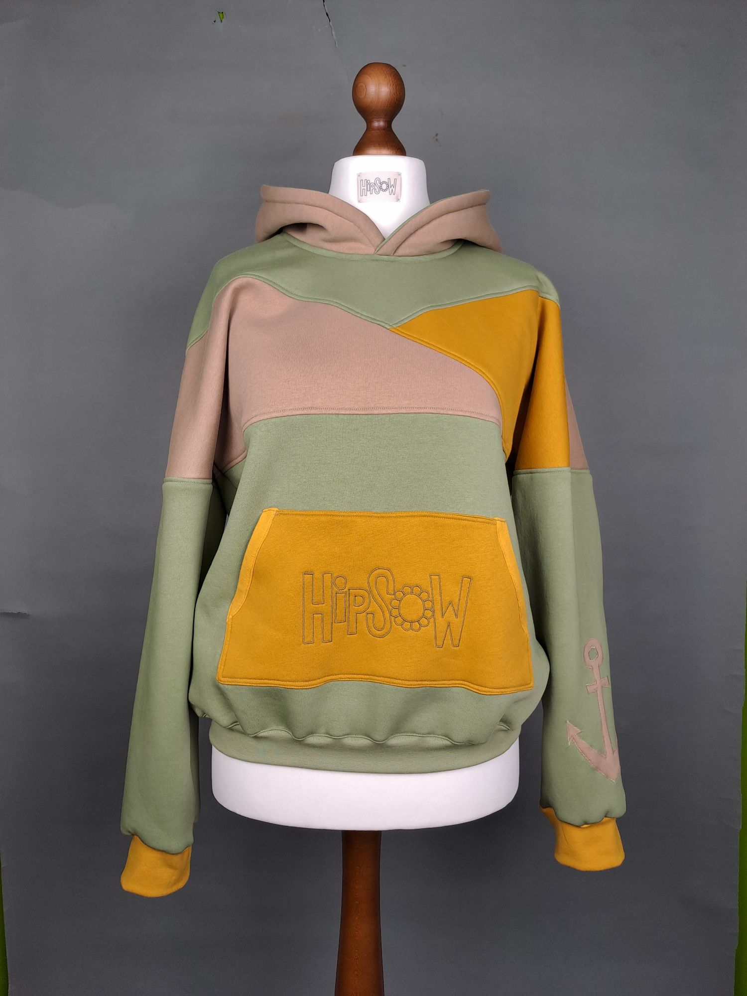 Hoodie auf Schneiderpuppe in verschiedenen Gelb-grüntönen mit Logostickerei
