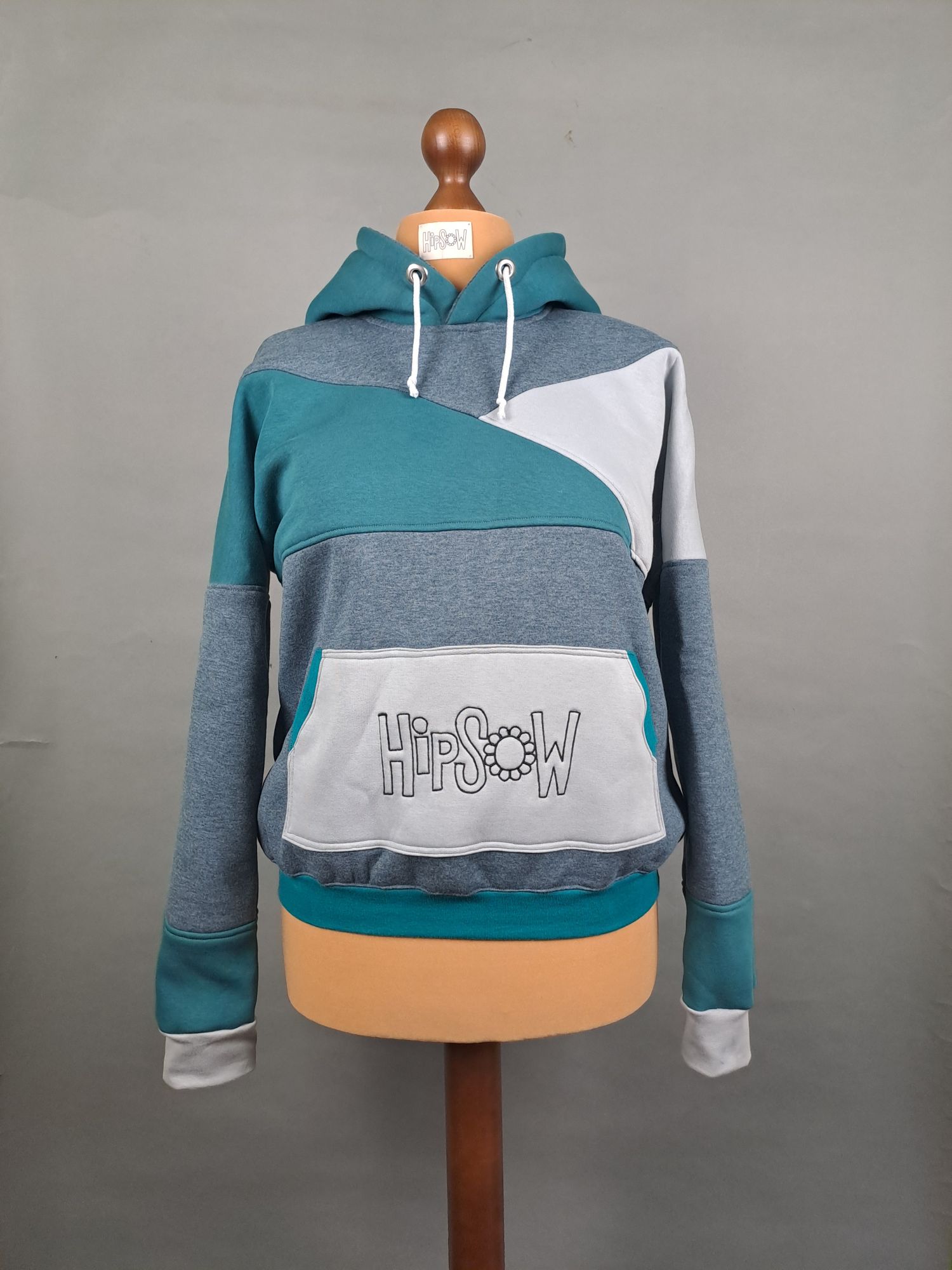 Hoodie auf Schneiderpuppe in verschiedenen Blautönen mit Logostickerei